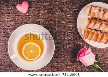 Tea with a slice of lemon, cakes, rose and a pink heart