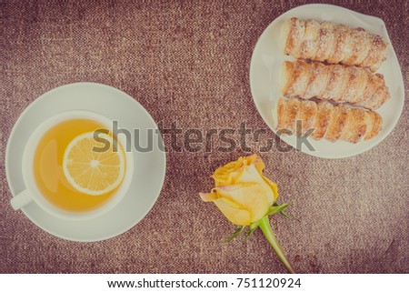 Tea with a slice of lemon, cakes and yellow rose