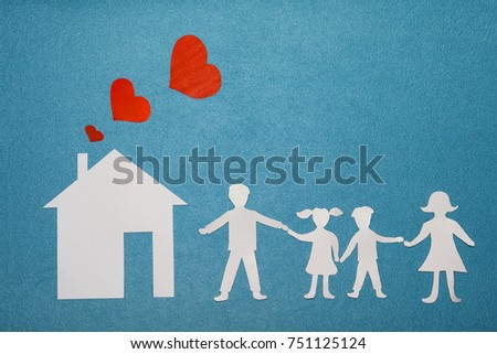 Family and home love concept. Paper house and family on blue textured background. Dad, mom, daughter and son hold hands. Red hearts from pipe at home. Happy family