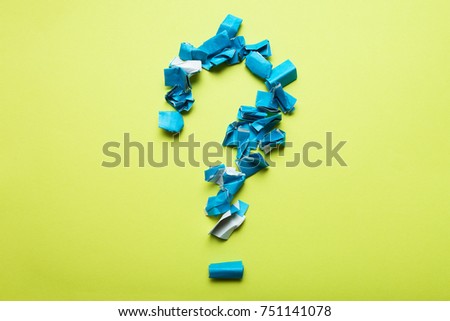 A large question mark from pieces of crumpled blue paper on a yellow background.
