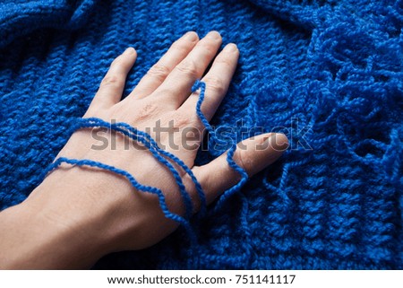 A woman's hand touches the blue gentle light and pleasant yarn, the thread for knitting, homemade clothes.