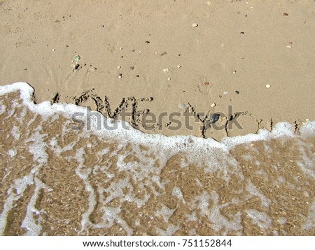 Inscription on the beach sand about love washed off by a wave
