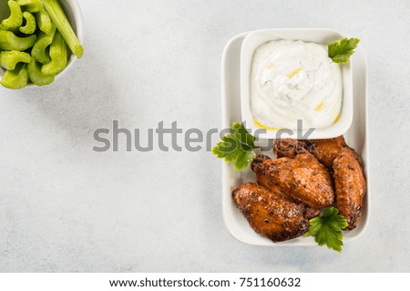 Homemade Buffalo chicken wings with blue cheese dip and celery sticks on light background