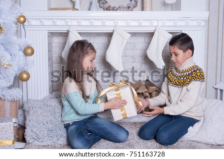 Merry Christmas and Happy Holidays concept. Portrait of little boy and girl. Family holiday. New Year's picture of brother and sister with gifts. Children   opening a gift at home in the living room. 