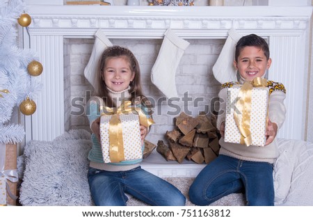 Merry Christmas and Happy Holidays concept. Portrait of little boy and girl. Family holiday. New Year's picture of brother and sister with gifts. Children   opening a gift at home in the living room. 