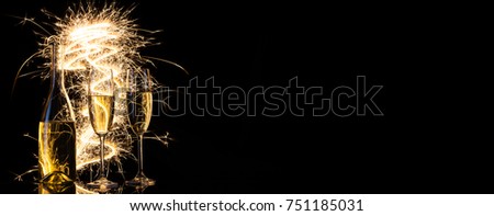 Bottle and glasses with champagne in sparks of Bengal lights. Black background. Silhouette. The concept of celebration. New Year celebration.