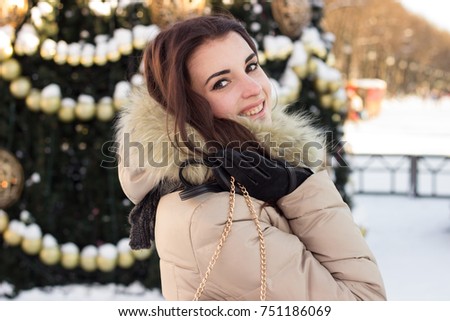 Young woman in winter park near christmas tree
