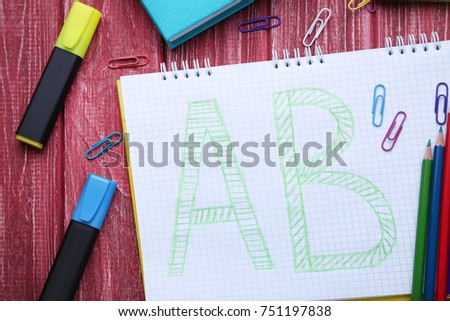 Handwritten letters in notebook with colored pencils on red wooden table