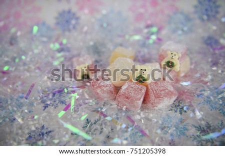 Christmas food photography picture in pastel colors of pink white and purple of traditional turkish delight confectionery cubes with small polar bear decorations and  snowflake pattern background