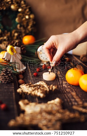 Christmas background with decorations and candles, candle on fire with woman hand
