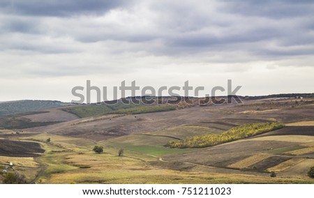 Autumn , amazing landscape view, meadow , hill covered with forest and golden leaves, above a river. A view in Europe, Moldova. Multicoloured horizon . Horizontal photo , along with big gray clouds.