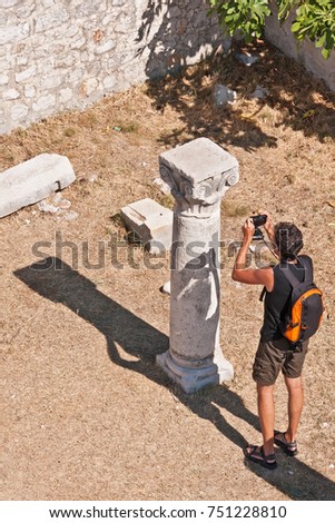 Tourist taking a picture of Roman ruins on island of Rab, Croatia during a hot summer day