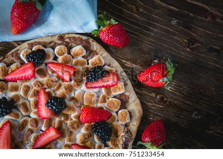 Wooden oven home made sweet pizza with topping of strawberries, blackberries, marshmallow and chocolate hazelnut cream.