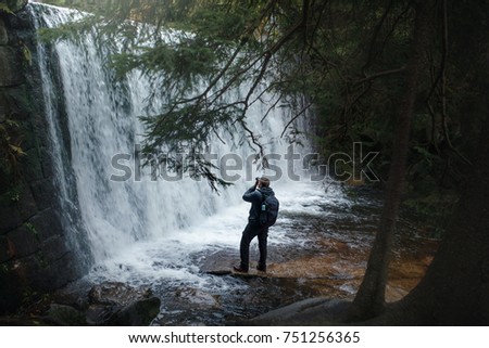 a man on a waterfall takes pictures of nature