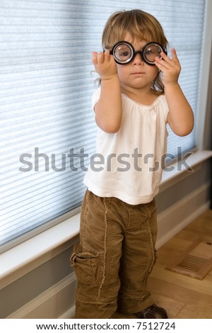 Cute, funny picture of a toddler girl wearing thick bottle mad scientist glasses.