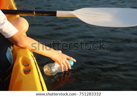 Children are reaching for a bottle of plastic waste in the ocean while paddling a kayaking
 Royalty-Free Stock Photo #751283332