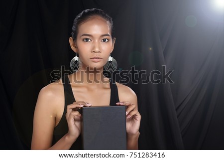 Your different text here. Pretty young asian model face woman holding empty blank board black box. studio lighting dark background portrait half body copy space for advertising area