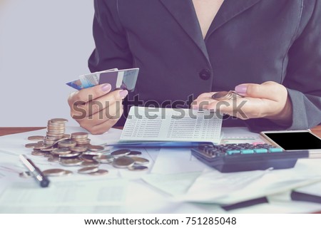  business woman hand calculating her monthly expenses during tax season with coins, calculator, credit card and account bank, idea for dept collection background  Royalty-Free Stock Photo #751285048