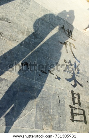 Simply street art calligraphy using water with a friendship shadow. Chinese word meaning wealthy for each generation.