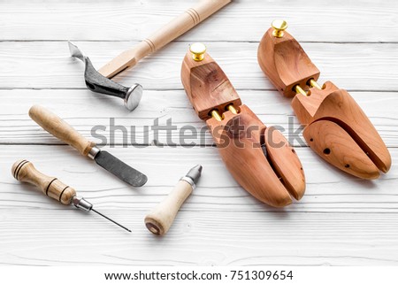 Tools for repair shoes. Wooden last, hammer, awl, knife, thread on white wooden background
