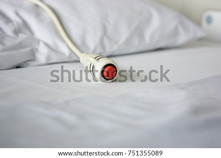 Hospital scene and medical equipment of emergency call button used by patient to communicate with nurses, lying on white clean bed with pillow.