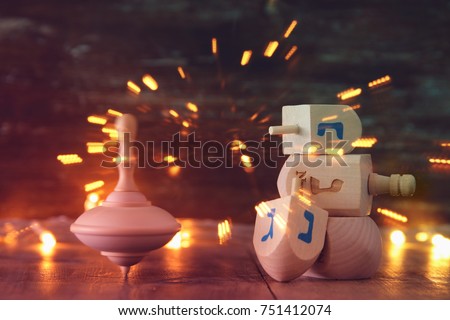 Image of jewish holiday Hanukkah with wooden dreidels colection (spinning top) and gold garland lights on the table