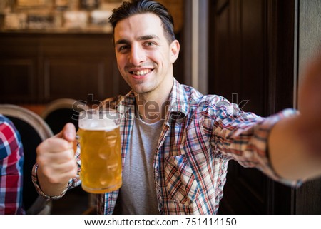 man with smartphone drinking beer and taking selfie at bar or pub