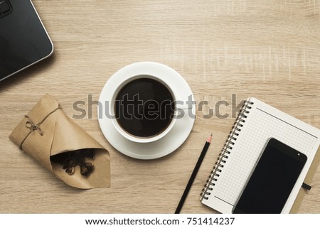 Office table with notepad, laptop, smart phone and coffee cup, dark chocolate. Top view, coffee-break