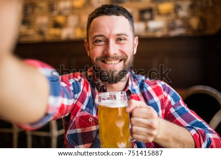 man with smartphone drinking beer and taking selfie at bar or pub