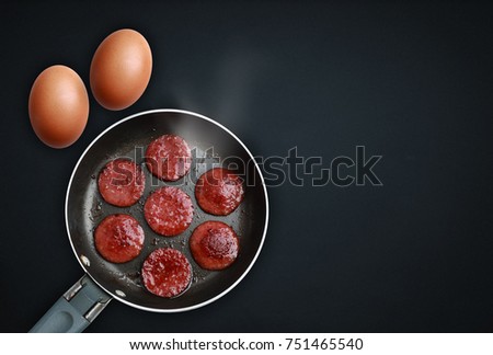 Organic brown egg and sausage on a black background.