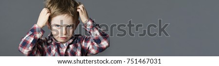 mischievous unhappy 6-year old kid with freckles scratching his hair for head lice or allergies, grey banner