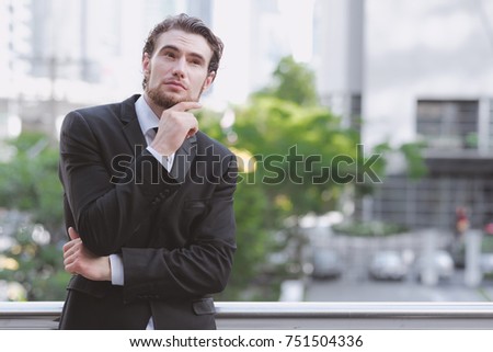 Confident young business man in black tie portrait. Handsome white male in black suit and tie, ginger hair and beard taken outdoor with natural light, confident business man concept.