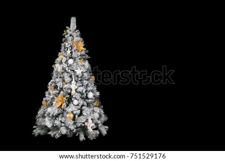 With snow covered christmas tree decorated in white and gold in front of a black background