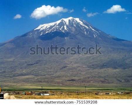 Mount Ararat (Greater Ararat), with snow on summit, on clear day with minimal clouds, and fields below, on the border between Turkey and Armenia, viewed from eastern Turkey. Royalty-Free Stock Photo #751539208