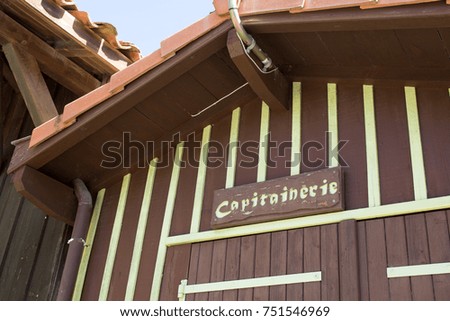 The brown and green wooden cabin of the harbor captain means capitainerie in French