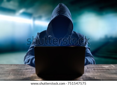 Hacker in front of his computer. Dark face. Blurred background