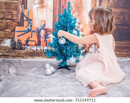 The little girl dresses up the Christmas tree