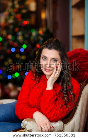 Beautiful girl in a red sweater near the Christmas tree.