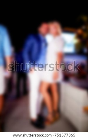 Blurred for backgroune. Ibiza night club. People  smiling and posing on cam during concert in night club party. Man and woman have fun at club. Boy and girl at night club party