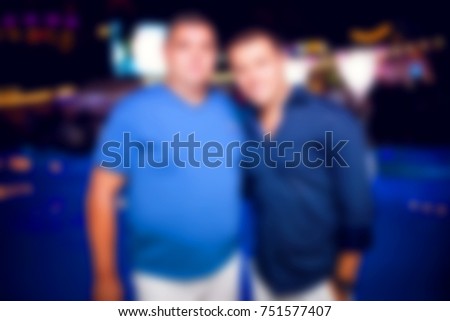 Blurred for backgroune. Ibiza night club. People  smiling and posing on cam during concert in night club party. Man and woman have fun at club. Boy and girl at night club party