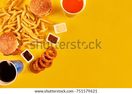 Fast food concept with greasy fried restaurant take out as onion rings, burger, fried chicken and french fries as a symbol of diet temptation resulting in unhealthy nutrition. Royalty-Free Stock Photo #751579621