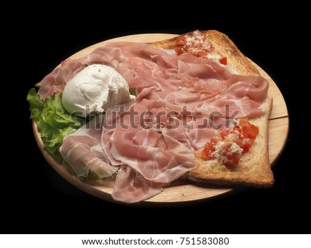 mozzarella, ham and tomato buschetta on a wood dish