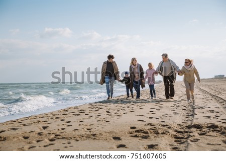 big multigenerational family walking together on beach at seaside Royalty-Free Stock Photo #751607605