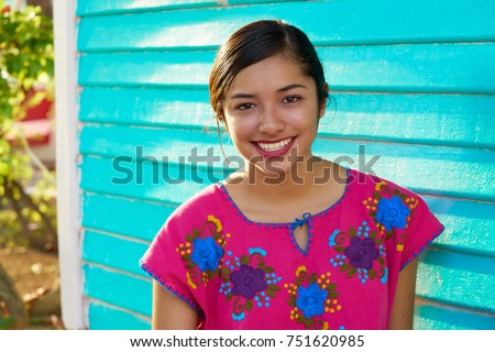 Mexican latin woman with mayan dress smiling in turquoise wall Royalty-Free Stock Photo #751620985