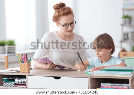 Female private tutor helping young student with homework at desk in bright child's room Royalty-Free Stock Photo #751634245