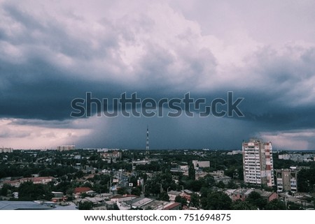 an enormous thunder-head with a strong rain approaches on a city