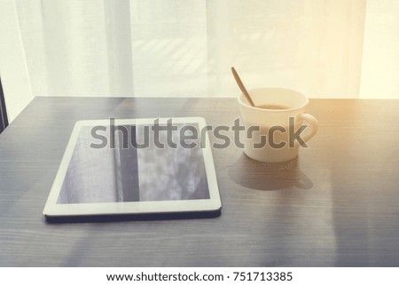 Wood Office table with blank screen  smartphone, tablet, cell phone and white coffee cup on white curtain windows texture background. golden light effect. view from front office table.