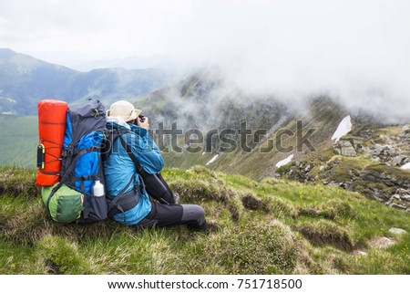 Mountain photographer and hiker with backpack and equipment outdoor on mountain peak