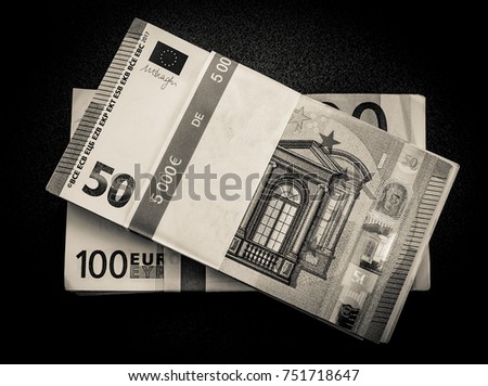 Black and white photo of stacks of Euro bills on a desk