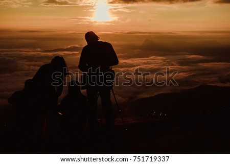 Silhouette traveler taking a photo landscape on top mountain with very mist and sunrise background.Happy and funny time with friends.